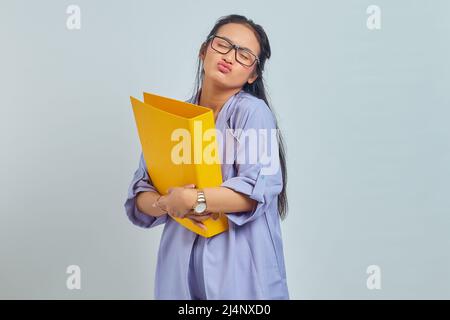 Portrait der schönen jungen asiatischen Frau umarmt gelben Ordner und geben Kuss isoliert auf lila Hintergrund Stockfoto