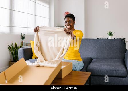 Junge Frau entpackt Tuch nach der Lieferung zu Hause Stockfoto
