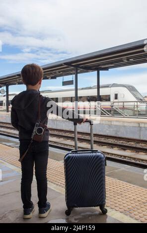 Kind Junge am Bahnhof mit Trolley. Reisen im Zug mit Kindern Konzept Stockfoto