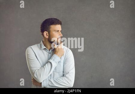 Der Mann hält seine Hand nachdenklich an sein Kinn Stockfoto