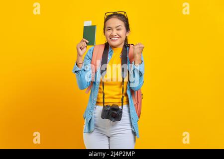 Porträt eines fröhlichen jungen asiatischen Reisenden, der auf gelbem Hintergrund die Bordkarte des Passes zeigt und Glück feiert. Beifahrer tr Stockfoto