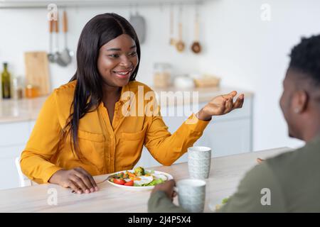 Glückliche Schwarze Frau Im Chat Mit Ehemann, Während Sie Mit Frühstück In Der Küche Stockfoto