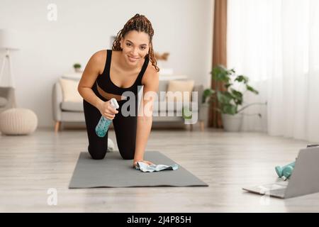 Sportliche African American Lady Reinigung Gymnastikmatte Zu Hause Stockfoto