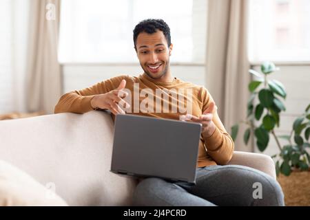 Arabischer Mann mit Laptop und Headset am Schreibtisch Stockfoto