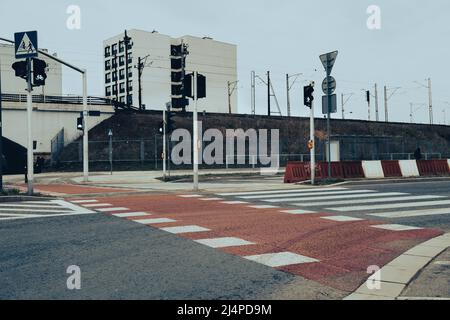 Fußgängerübergang, der durch eine Ampel gesteuert wird. Roter Teppich mit weißen Streifen. Stockfoto