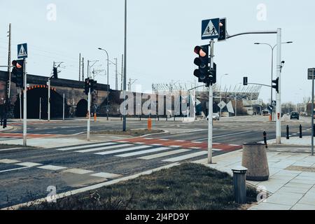 Fußgängerübergang, der durch eine Ampel gesteuert wird. Roter Fahrradteppich mit weißen Streifen. Stockfoto