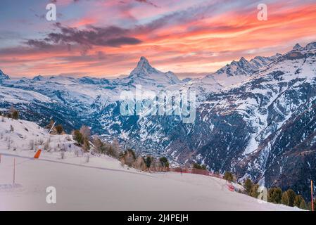 Malerische Aussicht auf die verschneite Bergkette gegen den bewölkten Himmel während des Sonnenuntergangs in den alpen Stockfoto