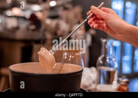 Weibliche Touristen tauchen Essen in Käsefondue am Tisch im Restaurant Stockfoto