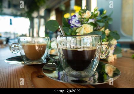 Ein Blumenstrauß und zwei Tassen Kaffee auf dem Tisch Stockfoto