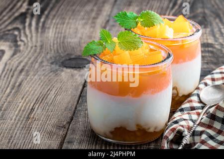 Weißer fruchtiger Joghurt in Gläsern auf Holztisch Stockfoto