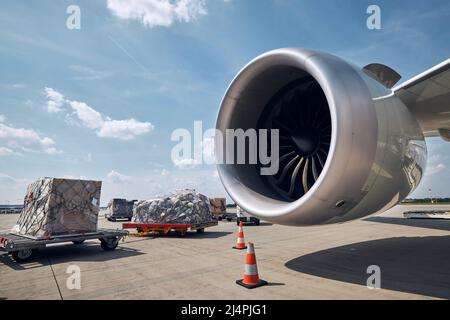 Vorbereitung Frachtflugzeug am Flughafen. Verladung von Frachtcontainern gegen den Düsenmotor des Flugzeugs. Stockfoto