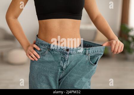 Afrikanische Frau Trägt Alte Große Jeans Nach Dem Abnehmen Innen, Abgeschnitten Stockfoto