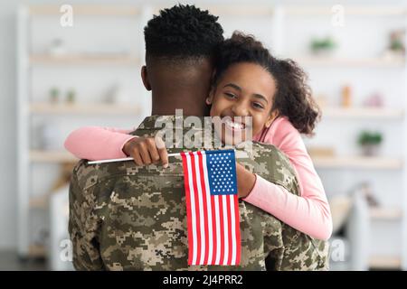 Glückliches schwarzes Mädchen begrüßt ihren Vater Soldat zu Hause Stockfoto