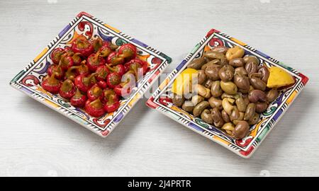 Ein paar traditionelle Schüsseln mit handentkernten marokkanischen Oliven und marinierten kleinen Chilischoten aus roter Kirsche aus nächster Nähe Stockfoto