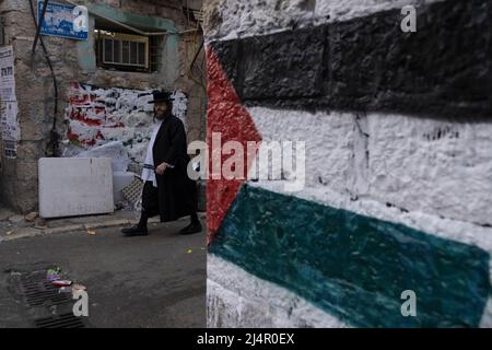 Ein orthodoxer Jude kommt an einer palästinensischen Flagge vorbei, die von extremen antizionistischen Haredi-Juden in Mea Shearim, einer ultra-orthodoxen Enklave in West-Jerusalem Israel, auf eine Wand gesprüht wurde Stockfoto