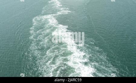 Eine schäumende, sprudelnde Spur auf der blauen Wasseroberfläche durch die Bewegung eines großen Schiffes auf See Stockfoto