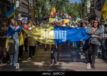 Barcelona, Spanien. 17. April 2022. Demonstranten halten während der Demonstration eine riesige ukrainische Flagge, während sie durch die Straße marschieren. Hunderte von Ukrainern mit Wohnsitz in Barcelona haben im Zentrum von Barcelona demonstriert, um ihre Unterstützung für den Widerstand der ukrainischen Bevölkerung zu zeigen. Kredit: SOPA Images Limited/Alamy Live Nachrichten Stockfoto
