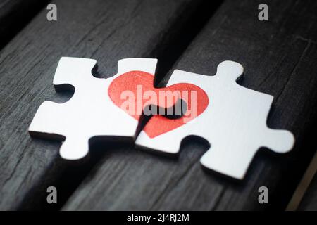 Rotes Herz ist auf die Stücke der Holzpuzzle nebeneinander liegend auf Holz- Hintergrund dargestellt. Liebe Konzept. St. Valentinstag Stockfoto