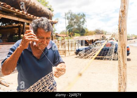 Ältere Latino-Fischer, die ein Wurfnetz weben, jagten Tintenfische in einem armen ländlichen Gebiet an einem Strand in Leon Nicaragua Stockfoto