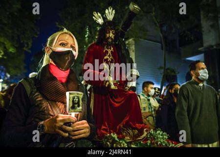 Eine Frau hält ein Bild von Jesus und hinter einer Darstellung von Christus, der sein Kreuz trägt, während des Kreuzweges in der Stadt Buenos Aires. Nach zwei Jahren der Pandemie kehrten die traditionellen Kreuzwegstationen am Karfreitag um 8:00 Uhr auf die Straßen von Buenos Aires zurück. Es wurde durch die Avenue of Mayo zur Kathedrale der Stadt mit dem Kardinal und aktuellen Erzbischof von Buenos Aires, Mario Aurelio Poli, durchgeführt, der das Bußkreuz trug. Stockfoto