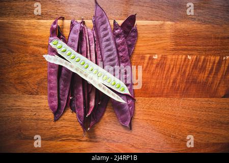 Stapel von Guaje-Samenschoten auf einem Holztisch mit einem offenen Samenschote in Oaxaca, Mexiko Stockfoto