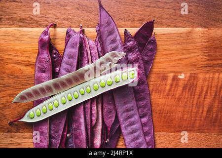 Stapel von Guaje-Samenschoten auf einem Holztisch mit einem offenen Samenschote in Oaxaca, Mexiko Stockfoto