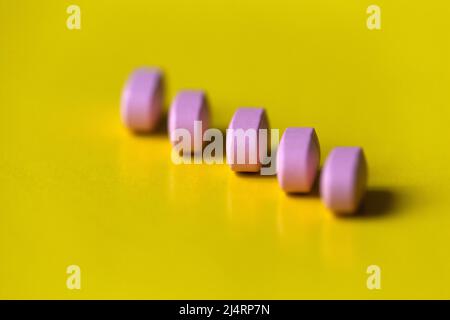 Lange rosa Pillen auf dem gelben Hintergrund. Medizin und Gesundheitskonzept. Stockfoto