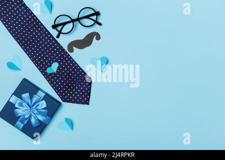Väter Tag Konzept. Geschenk Krawatte Brille Schnurrbart Herzen auf einem blauen Hintergrund. Draufsicht: Platz für flache, layierte Kopien Stockfoto