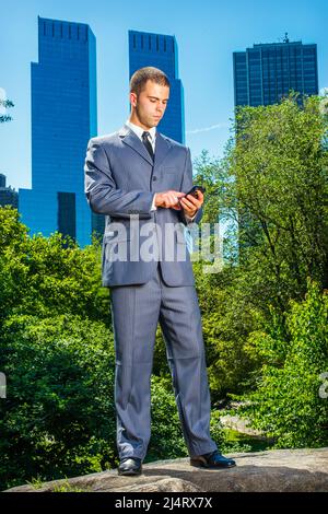 Junger Geschäftsmann schreibt. Formell in einem blauen Anzug, schwarzer Krawatte, Lederschuhen kleidet, steht ein junger Profi vor dem Business d Stockfoto