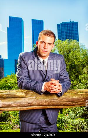 Porträt eines jungen Geschäftsmannes. Formell in einem blauen Anzug, schwarzer Krawatte, ein junger Profi steht vor dem Geschäftsviertel, RE Stockfoto