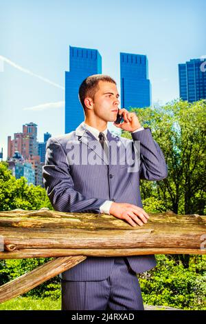 Junger Geschäftsmann am Telefon. Formell in einem blauen Anzug, schwarzer Krawatte, ein junger professioneller Kerl steht vor dem Geschäftsviertel, m Stockfoto