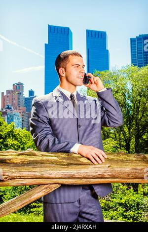 Junger Geschäftsmann am Telefon. Formell in einem blauen Anzug, schwarzer Krawatte, ein junger professioneller Kerl steht vor dem Geschäftsviertel, m Stockfoto