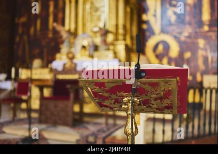 Detail eines vergoldeten Rednerpultes mit Buch und Mikrofon auf dem Altar einer Kirche Stockfoto