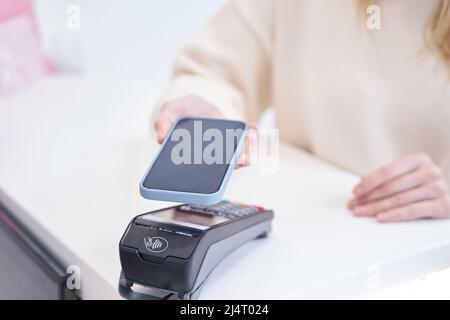 Kunde der Schönheitsklinik, der kontaktlose Zahlungen an der Rezeption abgibt Stockfoto