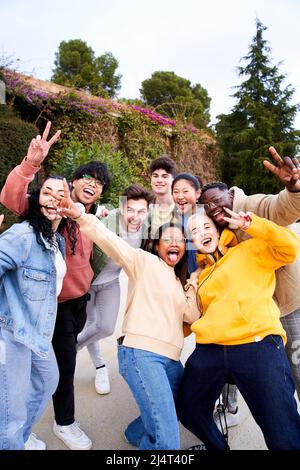 Vertikale Aufnahme einer großen Gruppe von fröhlichen motivierten und aufgeregt jungen Freunden, die Selfie-Portrait machen. Glückliche Menschen, die lächelnd auf die Kamera blicken. Konzept Stockfoto