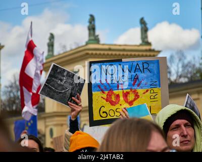 Mann hebt Banner stoppen den Krieg in der Ukraine steht auf blau-gelben Studio-Hintergrund. Demonstration mit Banner kein Krieg in der Ukraine. Kein Krieg, Krieg stoppen Stockfoto