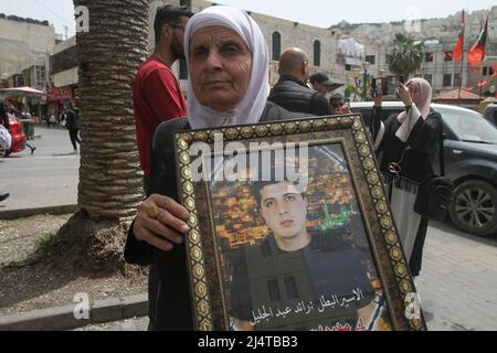 Nablus, Palästina. 17. April 2022. Eine Frau hält ein Porträt ihres Sohnes, der während der Demonstration in israelischer Haft war. Palästinensische Kundgebung anlässlich des Palästinensischen Gefangenentags (an dem die Palästinenser sich ihrer in israelischen Gefängnissen inhaftierten Freunde und Familienmitglieder gedenken), in der die Freilassung palästinensischer Häftlinge in israelischen Besatzungsgefängnissen gefordert wird. Kredit: SOPA Images Limited/Alamy Live Nachrichten Stockfoto