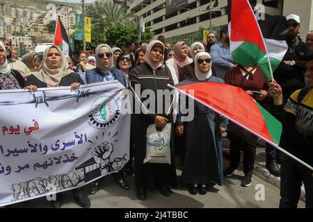 Nablus, Palästina. 17. April 2022. Palästinensische Demonstranten posieren während der Demonstration mit einem Banner und Fahnen. Palästinensische Kundgebung anlässlich des Palästinensischen Gefangenentags (an dem die Palästinenser sich ihrer in israelischen Gefängnissen inhaftierten Freunde und Familienmitglieder gedenken), in der die Freilassung palästinensischer Häftlinge in israelischen Besatzungsgefängnissen gefordert wird. Kredit: SOPA Images Limited/Alamy Live Nachrichten Stockfoto