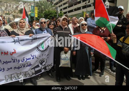 Nablus, Palästina. 17. April 2022. Palästinensische Demonstranten posieren während der Demonstration mit einem Banner und Fahnen. Palästinensische Kundgebung anlässlich des Palästinensischen Gefangenentags (an dem die Palästinenser sich ihrer in israelischen Gefängnissen inhaftierten Freunde und Familienmitglieder gedenken), in der die Freilassung palästinensischer Häftlinge in israelischen Besatzungsgefängnissen gefordert wird. (Foto von Nasser Ishtayeh/SOPA Images/Sipa USA) Quelle: SIPA USA/Alamy Live News Stockfoto