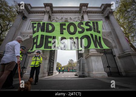 London, Großbritannien. 17.. April 2022. Die Demonstranten der Extinction Rebellion werfen über dem Eingang zum Marble Arch das Banner „BEENDET JETZT FOSSILE BRENNSTOFFE“ ab. Kredit: Guy Corbishley/Alamy Live Nachrichten Stockfoto