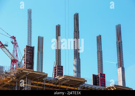 Schalungen und Metallstützen werden im modernen Bau von Tragkonstruktionen von Wohngebäuden gegen den blauen Himmel eingesetzt. Stockfoto