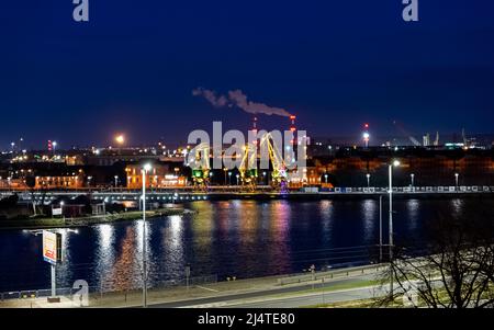 Die drei alten Hafenkrane von der Stettin Insel Lasztownia haben bunt beleuchtet. Stadt bei Nacht. Polen. Aus der Ferne ähnlich Dinosauriern. P Stockfoto