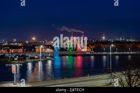 Die drei alten Hafenkrane von der Stettin Insel Lasztownia haben bunt beleuchtet. Stadt bei Nacht. Polen. Aus der Ferne ähnlich Dinosauriern. P Stockfoto