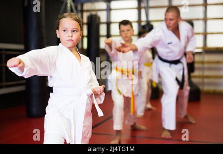 Karate Kids im Kimono, die Kata Moves ausführen Stockfoto