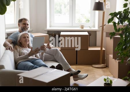 Reifes Paar, das digitale Tablets verwendet und Waren für ein neues Zuhause kauft Stockfoto