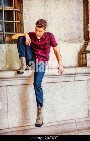 Mann, Der Nach Draußen Denkt. Kleid in einem kurzen Ärmel, schwarz, rot gemustertes Hemd, Jeans, Stiefel Schuhe, Ein junger, gutaussehender Kerl sitzt am Fenster und senkt sich Stockfoto