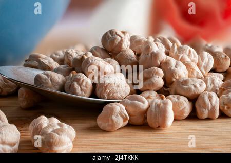 Makrofotografie, rohe oder ungekochte Kichererbsen auf einem Löffel mit blauer Zwiebel und Tomate auf dem Hintergrund Stockfoto