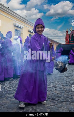 Antigua, Guatemala. Junge schwingt einen Weihrauch, während er einer religiösen Prozession während der Heiligen WocheJ, La Semana Santa, vorgeht. Stockfoto