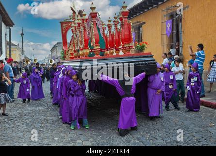 Antigua, Guatemala. Jugendliche Jungen, die während der Karwoche einen Schwimmer in einer religiösen Prozession tragen, La Semana Santa. Stockfoto