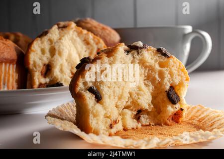 Muffins mit Schokoladensplittern auf einem weißen Teller mit einer weißen Tasse Kaffee im Hintergrund. Stockfoto